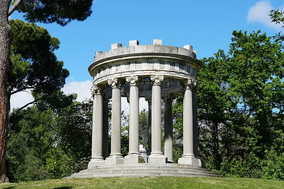 The Templete de Baco among trees beneath a blue sky
